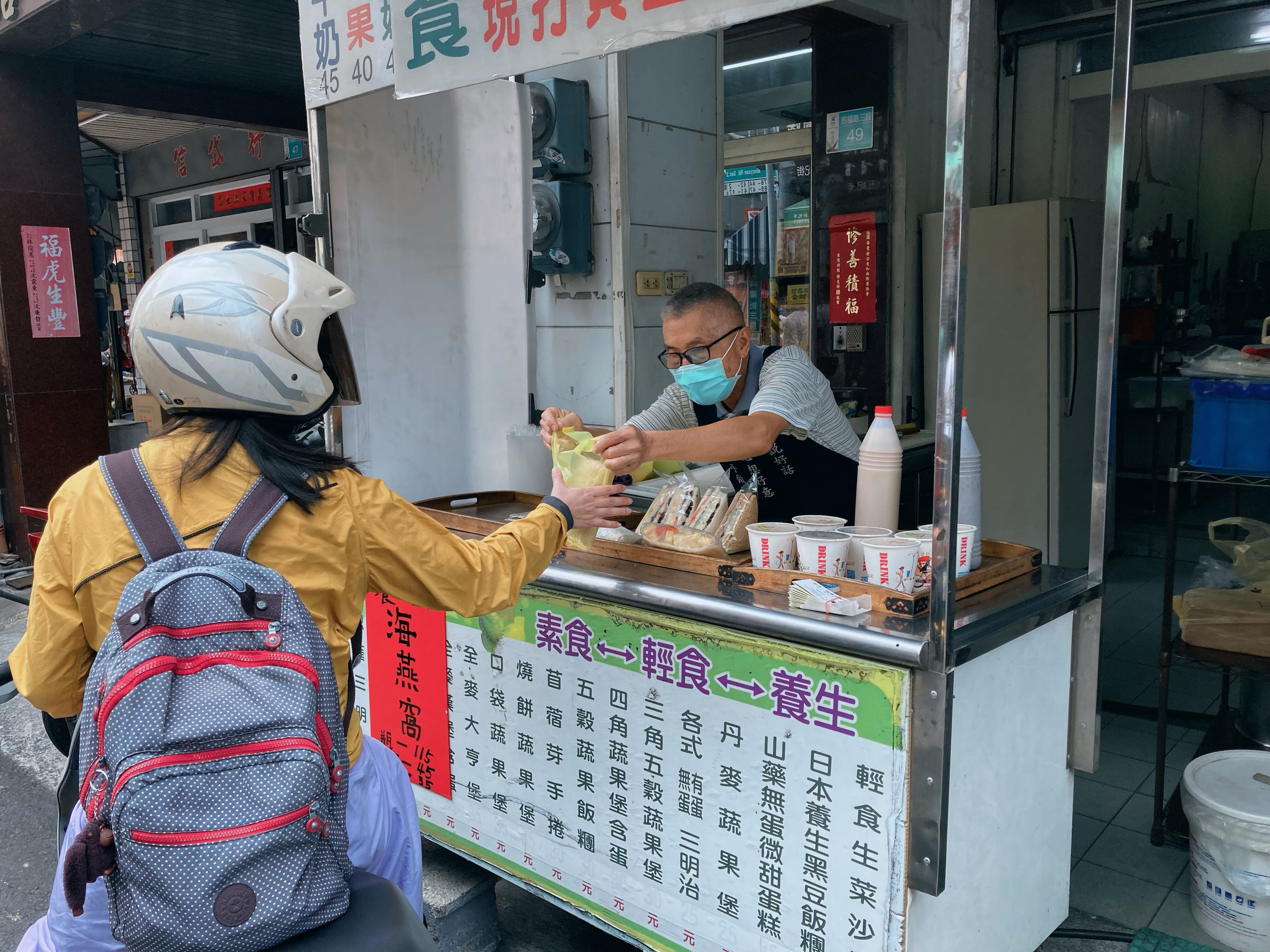 楊阿伯在舊早餐店窗口將餐點交給客人